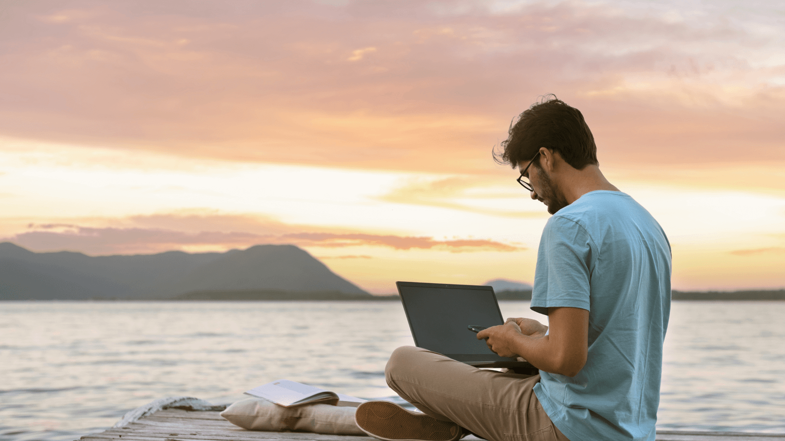 Digital nomad working on laptop at sunset beach