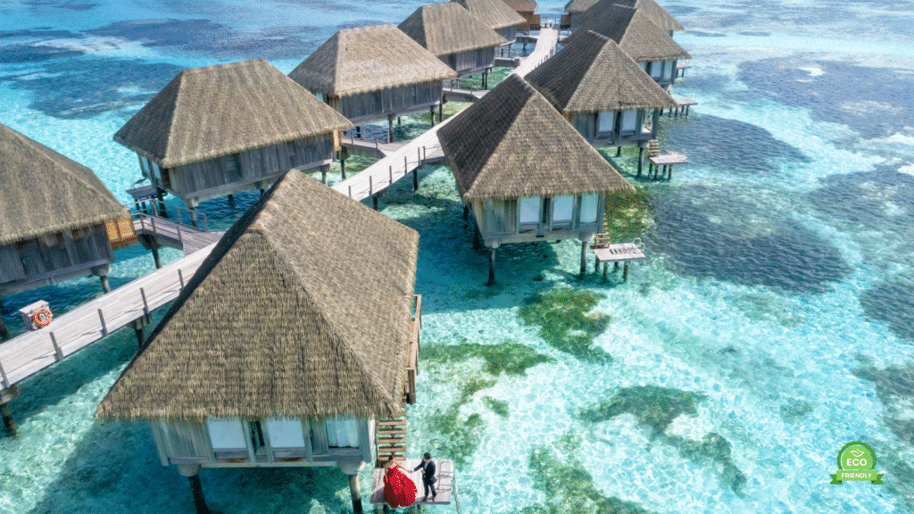 Over-water bungalows on a wooden boardwalk above a turquoise lagoon at sunset