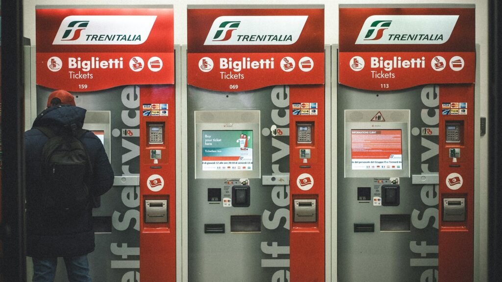 Traveler using train ticket machines at a European railway station while booking train travel in Europe