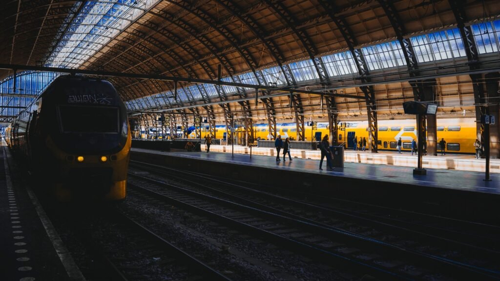 Vibrant scene at Amsterdam Central Station featuring iconic yellow trains and ornate architecture. Photo by Chris Oberman on Pexels.