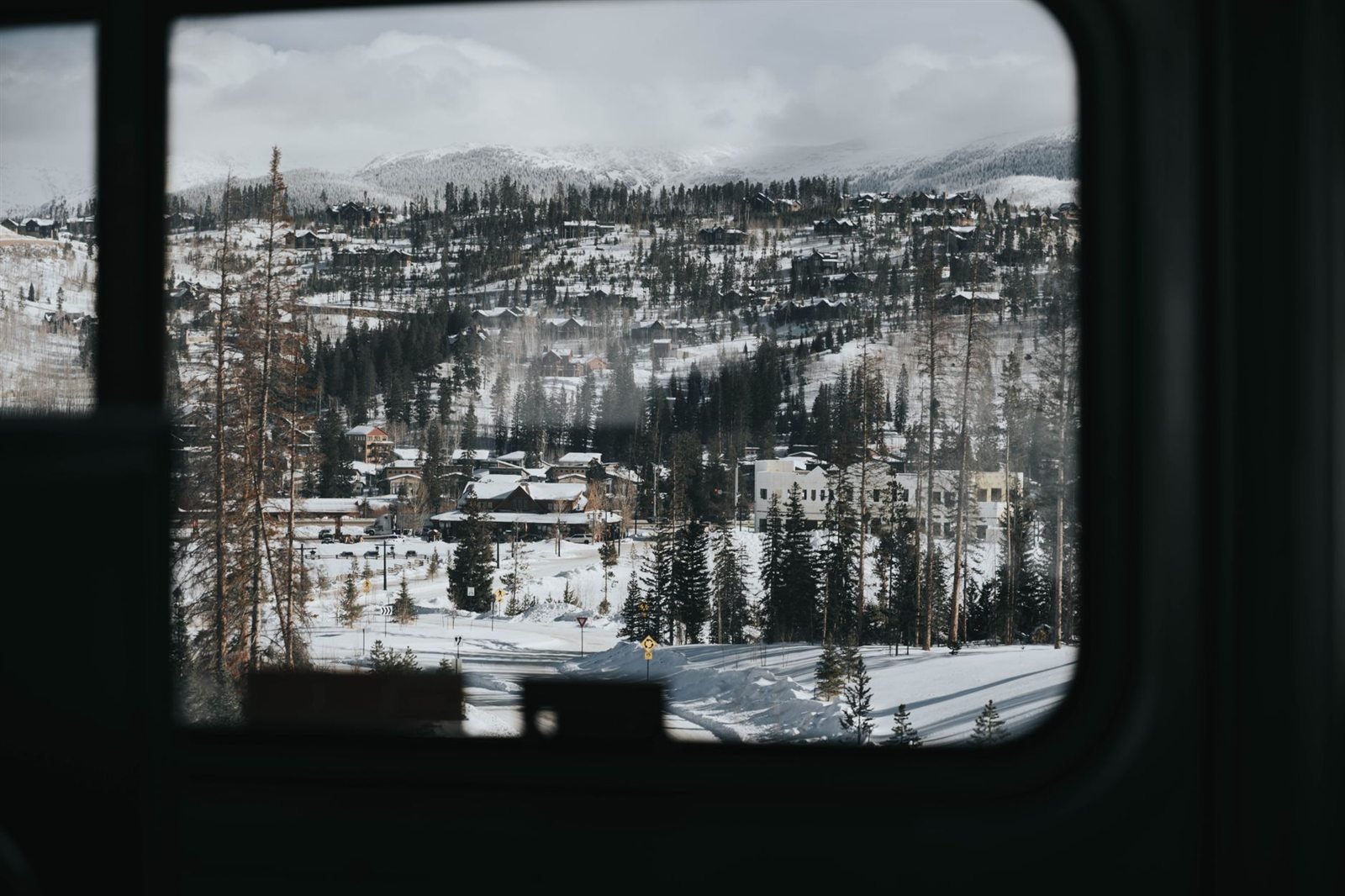 A view through a train window of snow-covered forest and hills